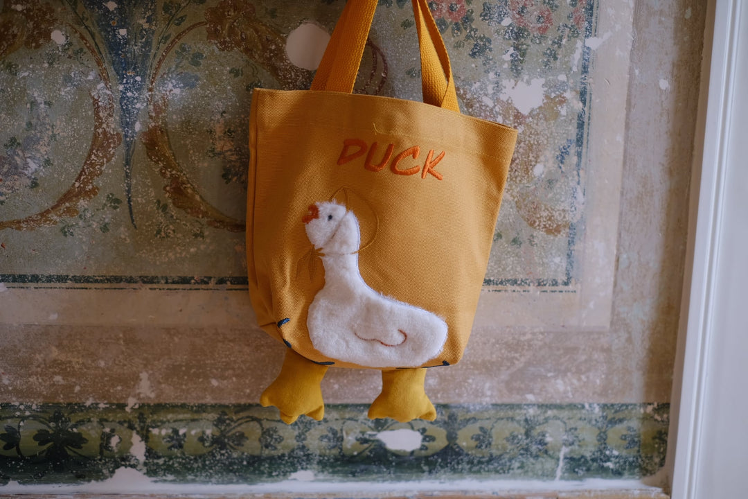 The Quacky Duck Embroidered Tote Bag in sunshine yellow, showcasing the adorable duck design with fluffy fabric and embroidered details, with "DUCK" text above.