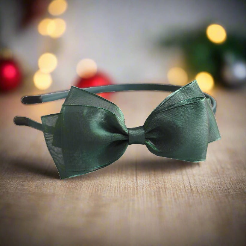 A charming headband featuring a large silk yarn bow in a soft green hue, perfect for adding a delicate touch to any girl's ensemble. The triple-layer bow design offers a luxurious and layered look.