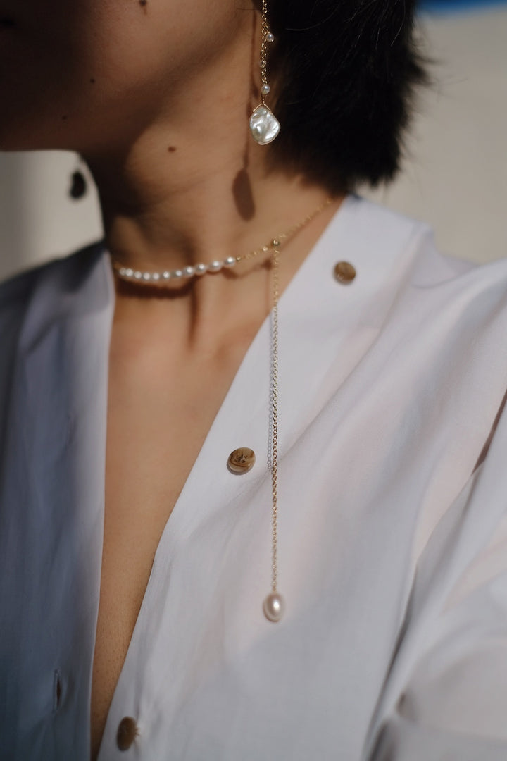 The necklace adorns a model’s neck, styled as a short, elegant choker. The pearls curve gently along the collarbone, capturing the serene grace of a moonlit night.