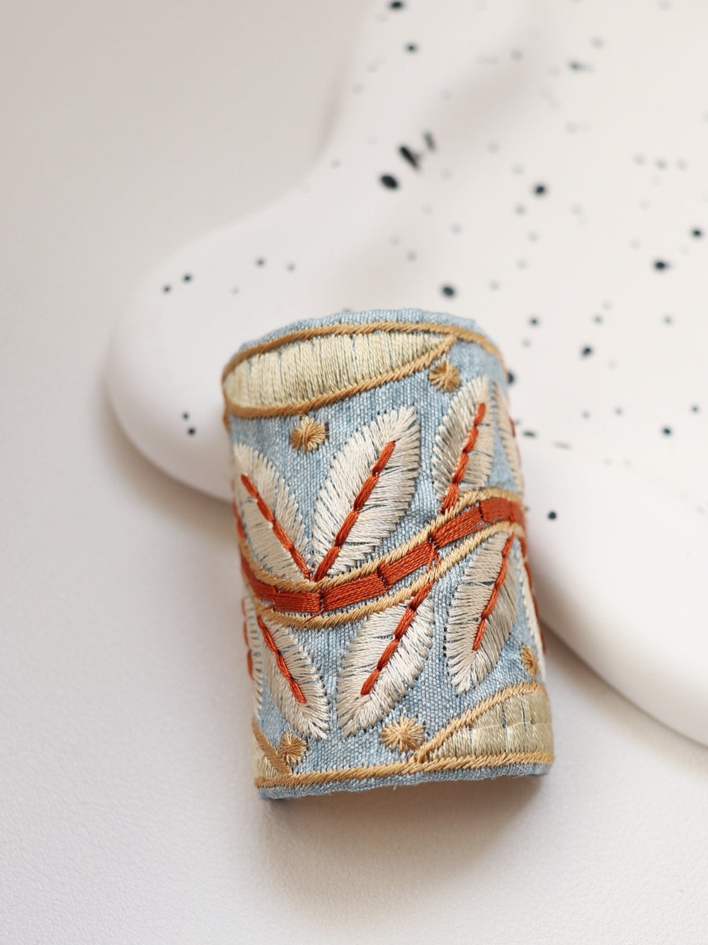 The Autumn Sky hair wrap features a cool blue fabric embroidered with warm, autumnal gold and orange leaves. This design beautifully captures the transition of seasons, adding a touch of nature-inspired elegance to your style.