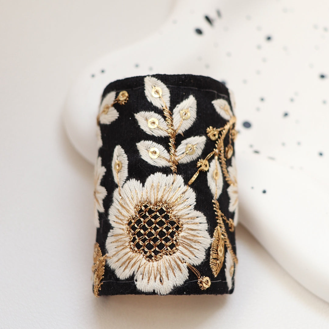 The Midnight Sakura hair wrap features a striking black fabric with elegant white and gold sakura blossoms. This timeless and classic design adds a touch of sophistication and contrast to any look.