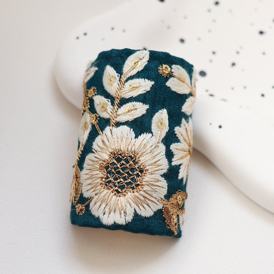 The Twilight Sakura hair wrap showcases a rich blue fabric embroidered with white and gold sakura flowers. This exquisite design captures the serene beauty of sakura in full bloom, perfect for enhancing your hairstyle with elegance.