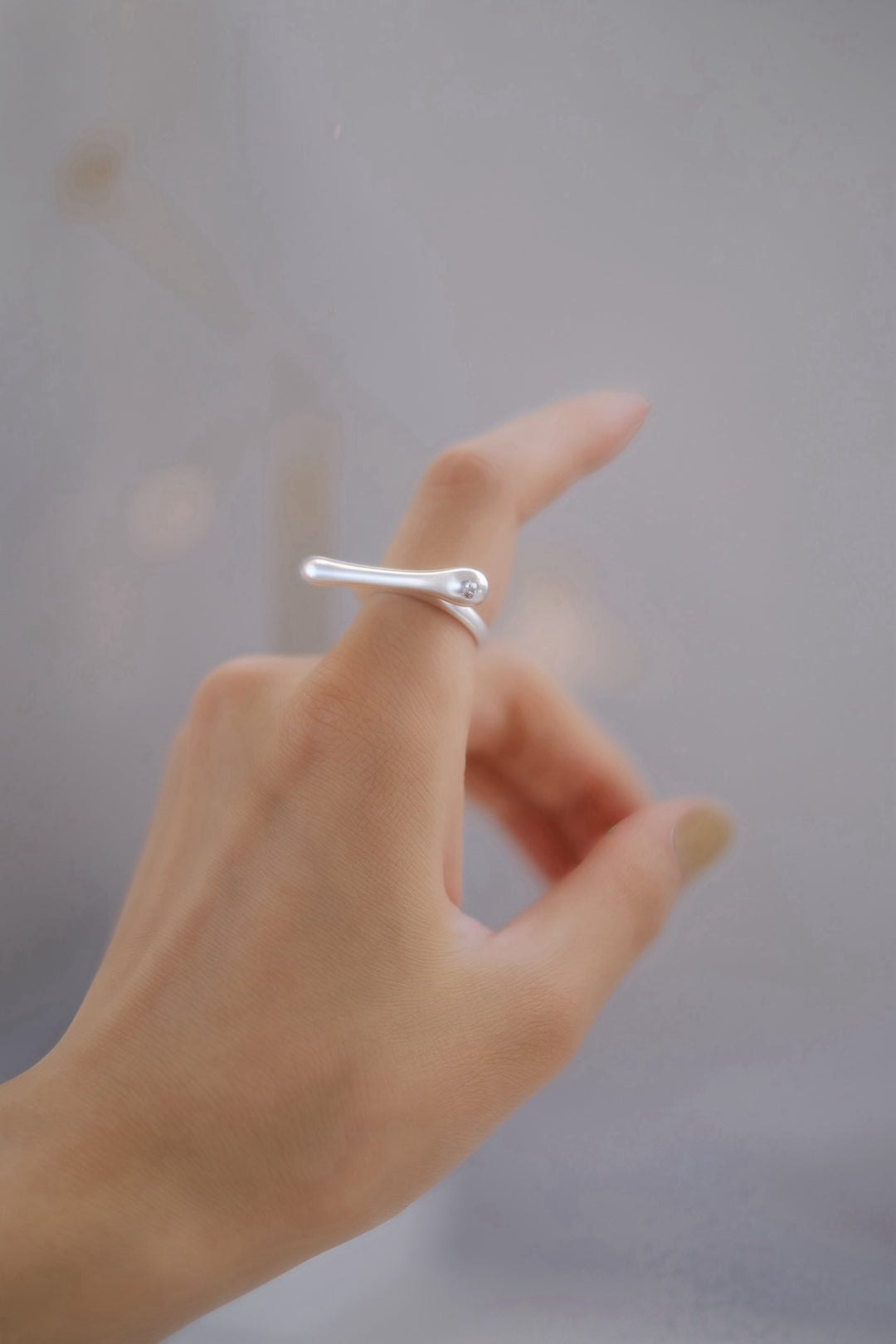 The Bone sterling silver ring worn on a woman's hand, showcasing its elongated, bold design. The sleek, polished surface catches the light, making it a striking statement piece for any contemporary jewelry lover.