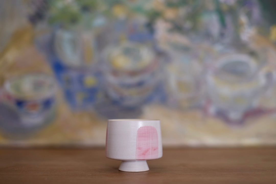 A side view of the ceramic cup showcases its modern, clean lines and blush pink accent. The smooth, rounded form and small footed base give it a balanced and elegant look, perfect for an espresso or a delicate tea ritual.