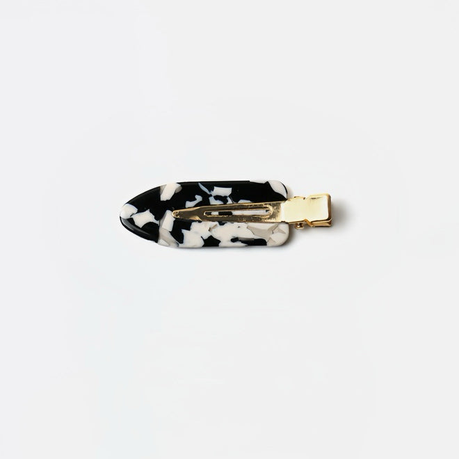 The Tortoiseshell Black and White no-crease hair clip is featured here, highlighting its modern and chic pattern. At 6 cm long, this clip combines style and functionality, providing a sleek hold without leaving any creases.