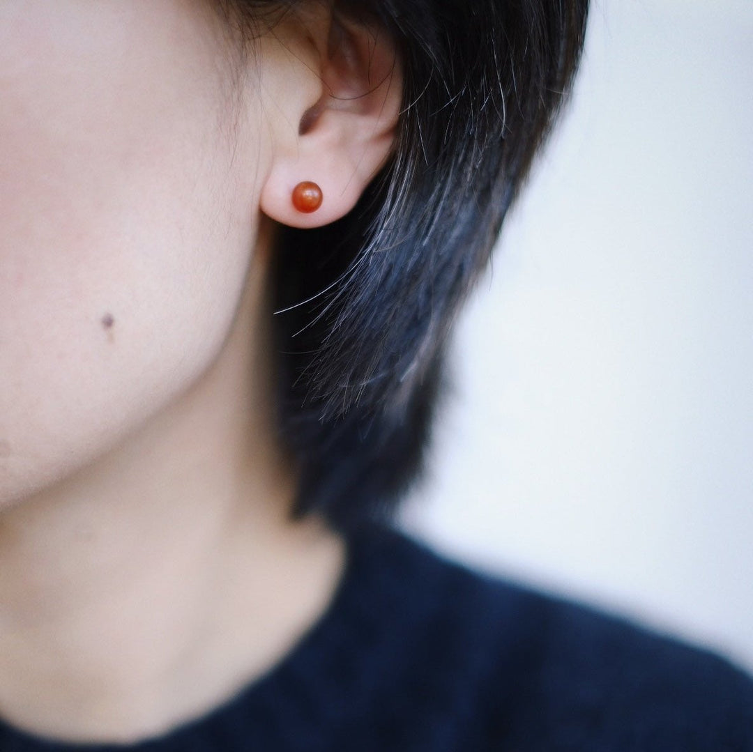 A close-up of a model's ear adorned with the 6mm red onyx stud earring. The simplicity and charm of the earrings are highlighted, showing how they complement the model's outfit effortlessly.