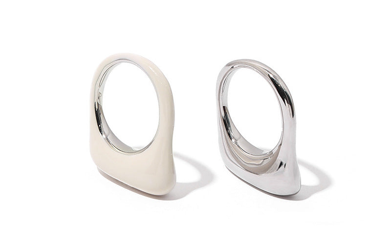 Placed against a stark white background, the white and silver rings stand out with their distinct textures and finishes. The simplicity of the backdrop enhances the rings' modern, clean lines, making them the focal point.