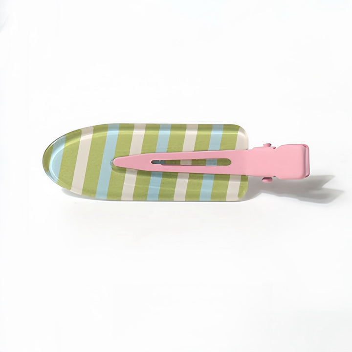 A detailed view of the Striped Resin Hair Clip, showcasing stripes in sky blue, grass green, and beige. The bright pink handle contrasts beautifully with the stripes, making this 6 cm clip a lively and stylish addition to your accessory collection.