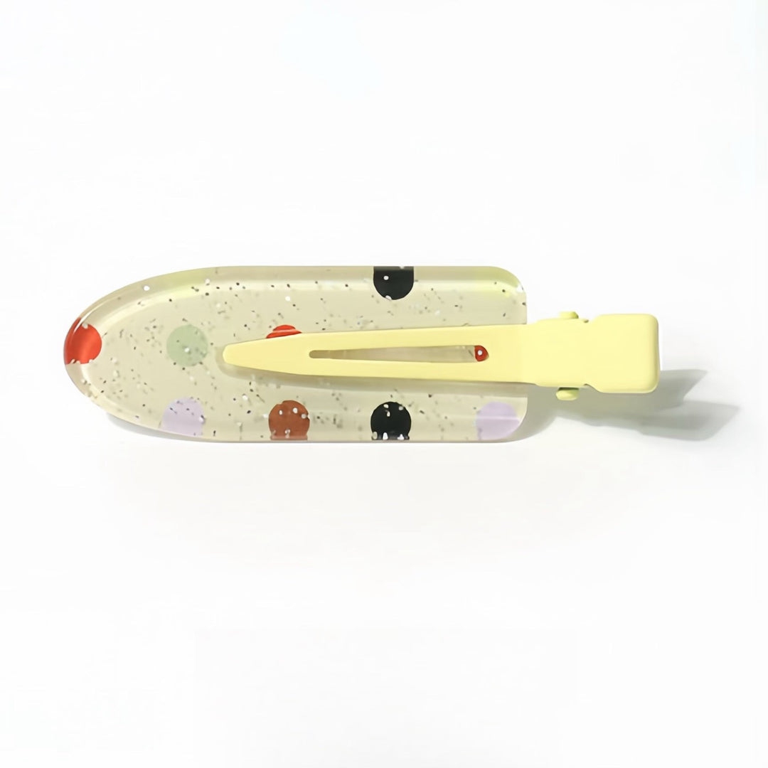 The Light Yellow Polka Dots Resin Hair Clip shows off its playful multi-colored polka dots in black, red, brown, light purple, and light green. The 6 cm clip is complemented by a light yellow handle, perfect for adding a touch of whimsy to any hairstyle.