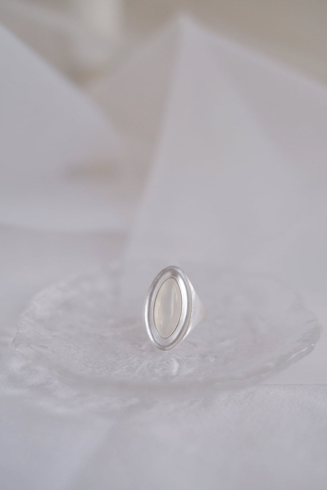 A detailed close-up of the Goddess Silver Open Ring featuring the translucent white agate gemstone, showcasing its elegant eclipse shape and the smooth, matte finish of the sterling silver band.