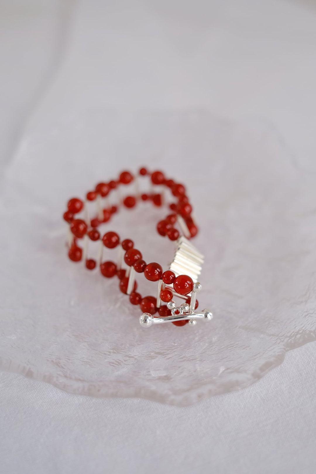 A close-up of the red onyx bracelet, showcasing its vibrant red onyx beads and unique armor-like silver clasp.