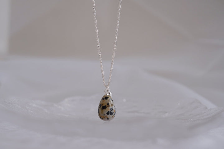 The Teardrop necklace with a small dalmatian jasper pendant showcases the stone's distinctive black spots and polished finish.