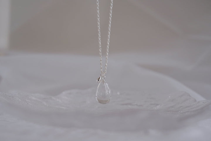 The teardrop necklace with a small white crystal pendant has a transparent finish.