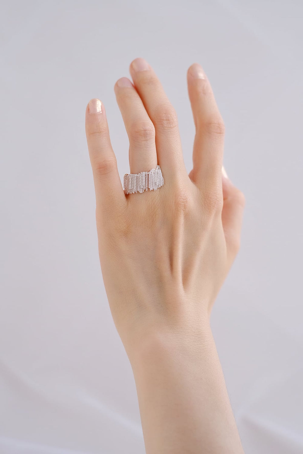 The intricate silver tassels flow gracefully over the finger.