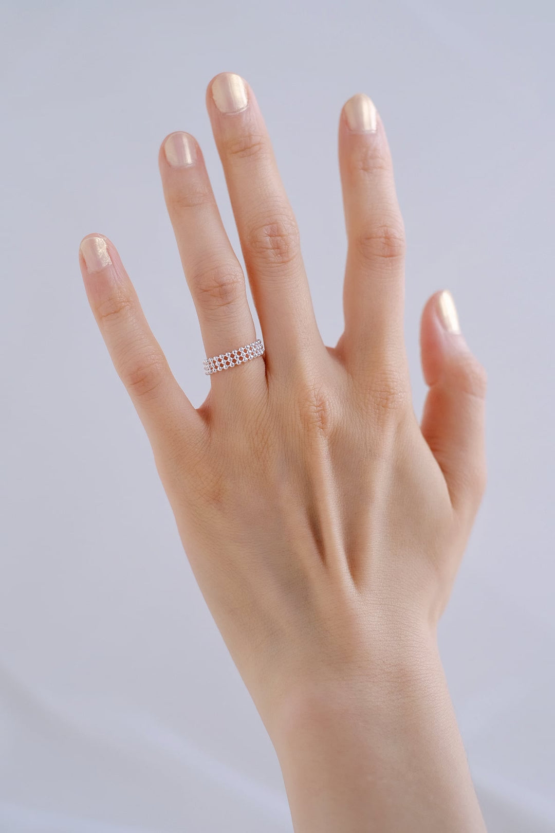 A close-up view of the adjustable silver ring worn on a hand, highlighting its delicate and elegant design against the natural skin tone.