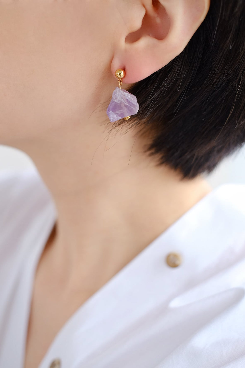 A close-up of a person wearing the purple amethyst earring, showcasing its calming and stress-relieving properties.