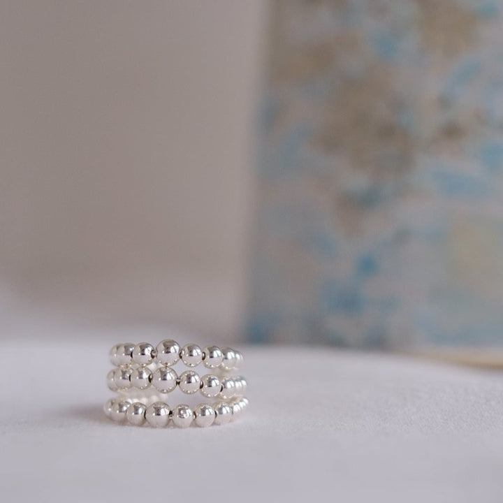 A close-up of the silver Hail ring, showcasing its chunky design and three layers of silver beads stacked next to each other. 