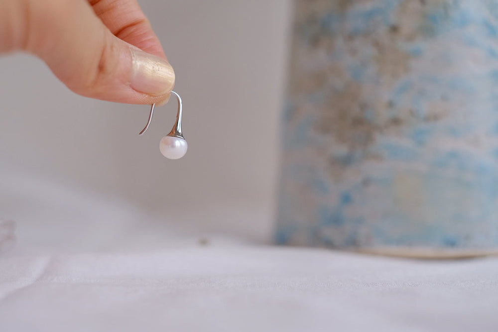 A hand holding one earring, highlighting the detail and craftsmanship of the design.