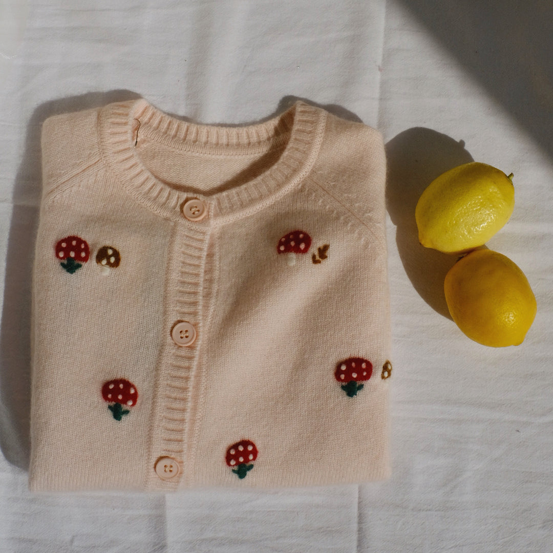 Delicate pink buttons seamlessly blend with the yarn color, adding a charming detail to this adorable piece.