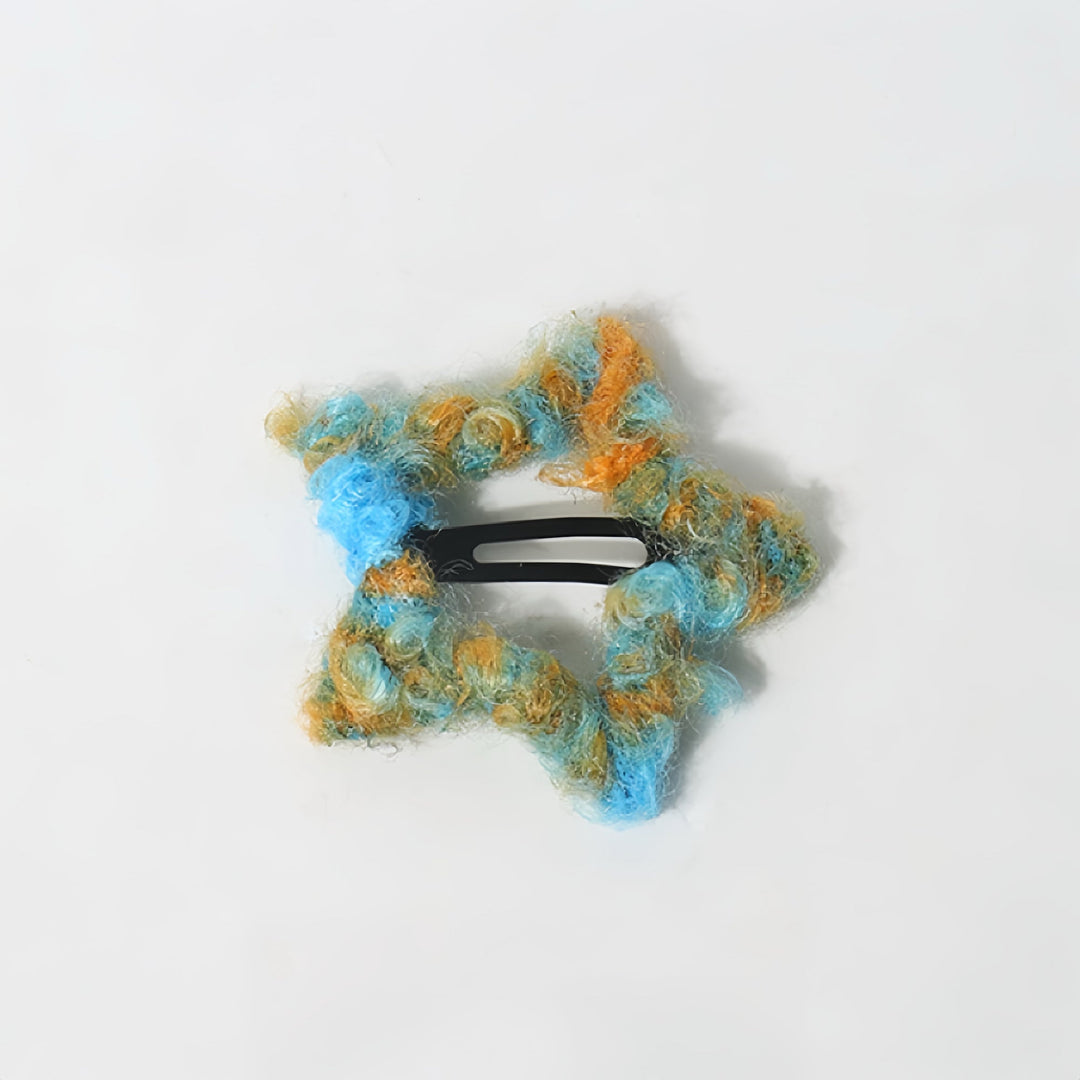 The fluffy, wooly star-shaped hair clip in blue, arranged on a white background.