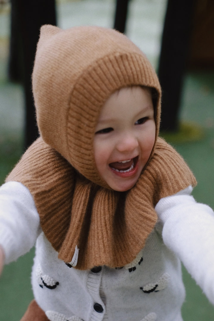 The hat has a rounded shape and fits comfortably over the child’s ears, providing both style and warmth.