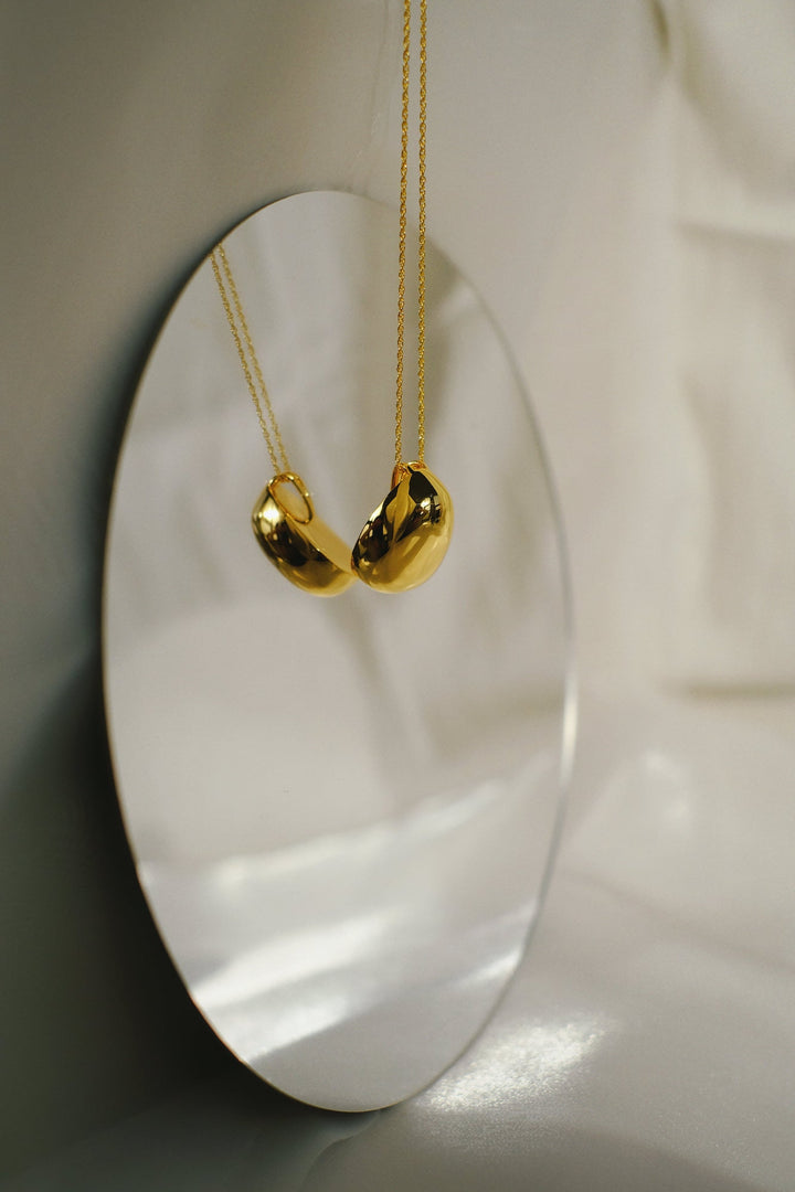 Detail shot of the oval pendant on the gold necklace.