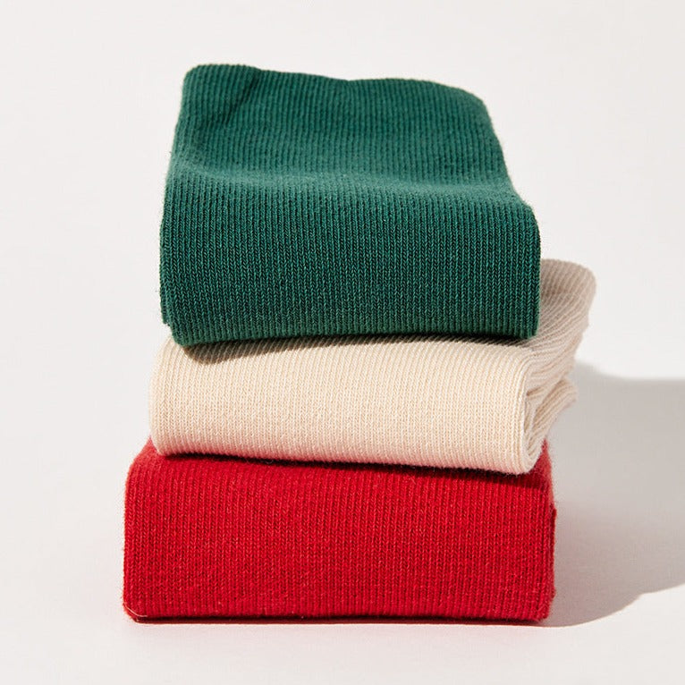 Neatly folded socks in green, white, and red, showcasing the variety of designs and the high-quality material.