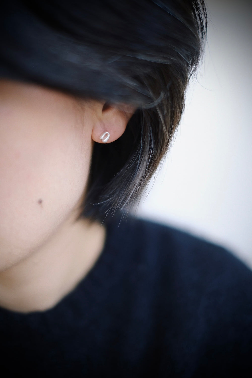 A model wearing one sterling silver Mini Horseshoe earring, demonstrating the subtle yet charming effect it has on her look.