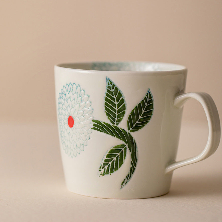 An elegant display of our premium porcelain coffee mugs adorned with handcrafted green Dahlia patterns, perfect for adding a touch of sophistication to your morning routine.