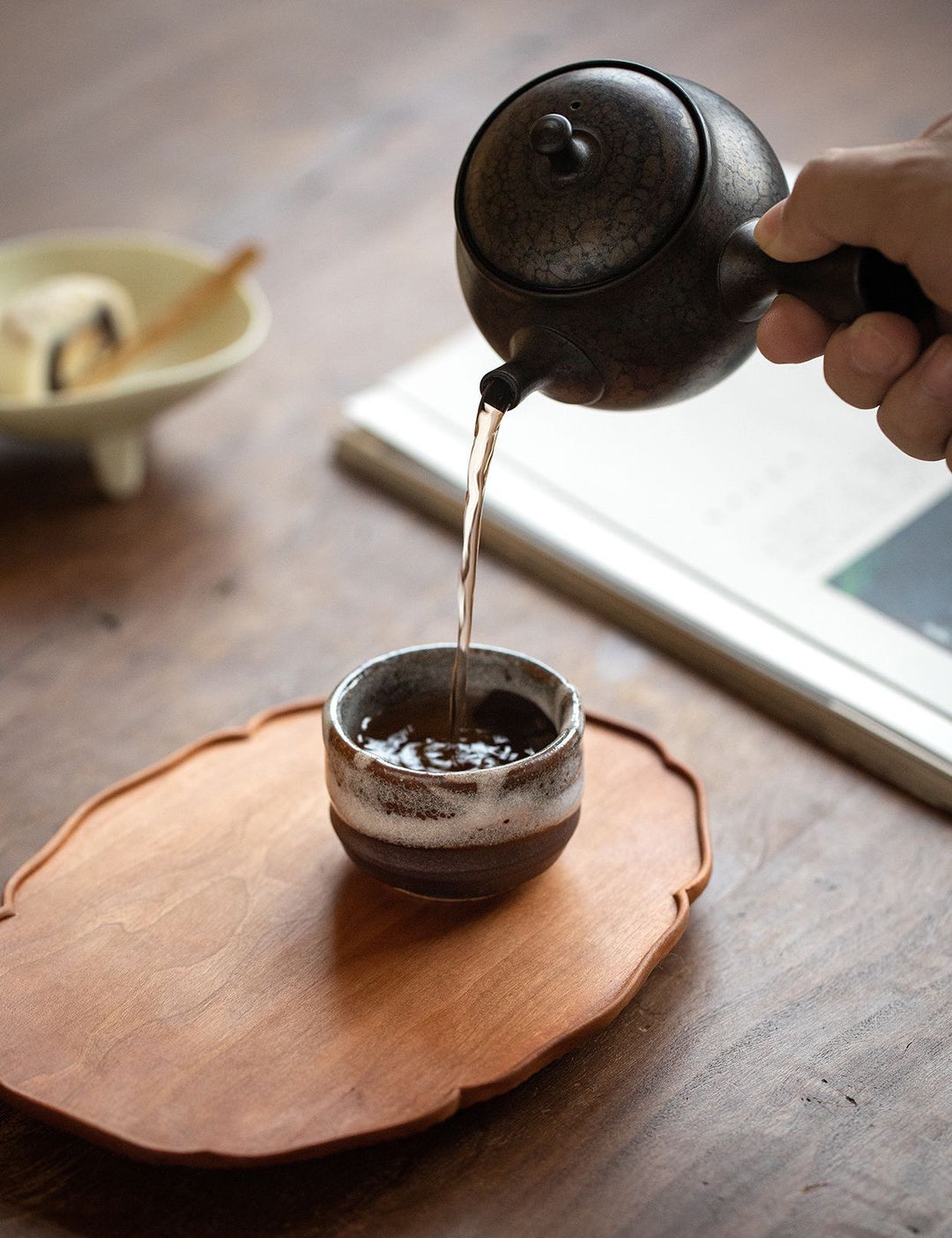 A person pouring tea into one of the Minoyaki cups.