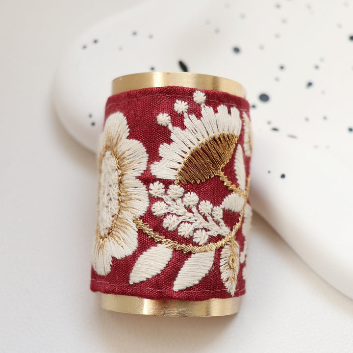 The Crimson Dahlia hair wrap boasts a rich, deep red background with intricate white and gold floral embroidery. This vibrant and bold design is perfect for making a statement and adding a pop of color to any outfit.