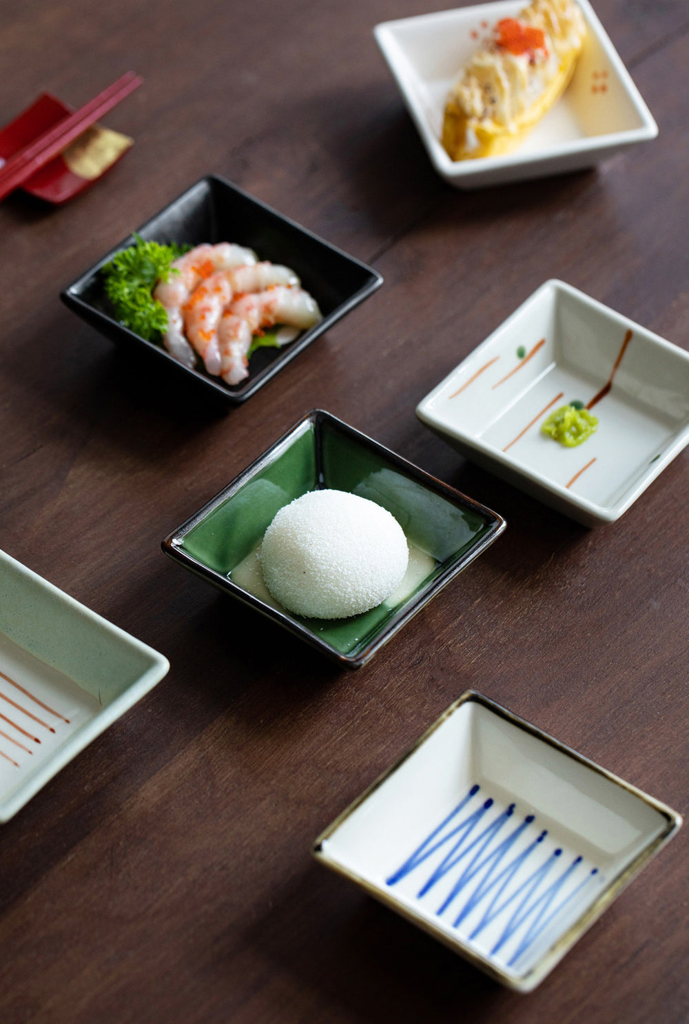 The plates in use, each filled with different appetizers and side dishes, showcasing how the designs complement the presentation of the food, making the dining experience visually appealing.