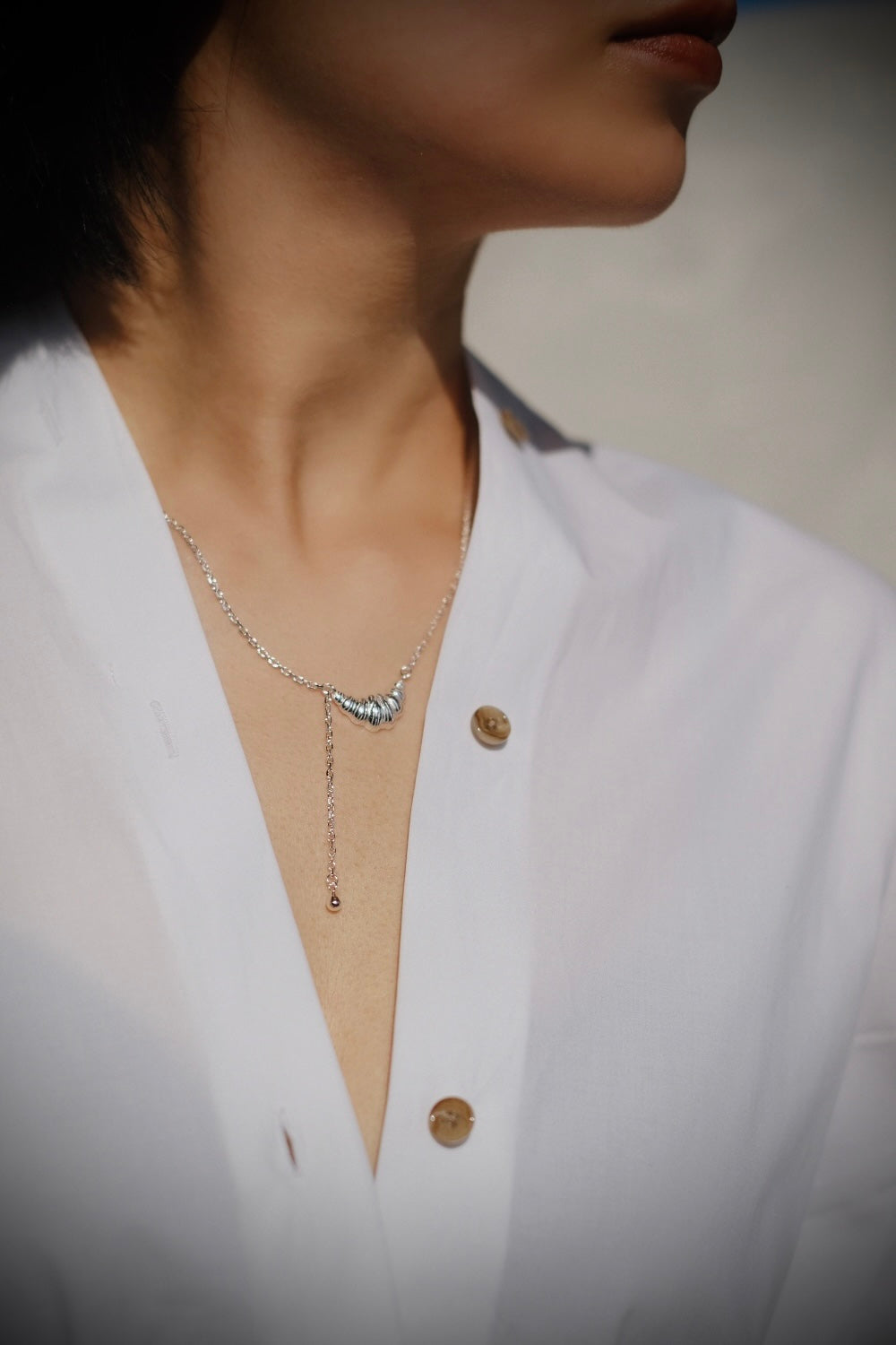 Worn by a model, the Croissant Sterling Silver Necklace rests gracefully on the collarbone, its crescent pendant catching the light.