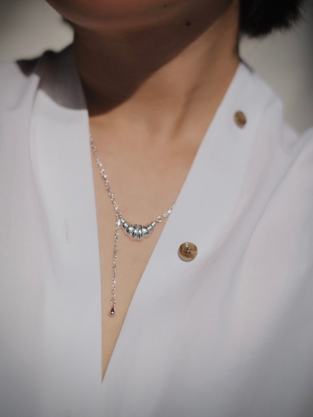 This image showcases the necklace’s flattering fit and how it adds a subtle yet sophisticated charm to any outfit, from casual to formal.